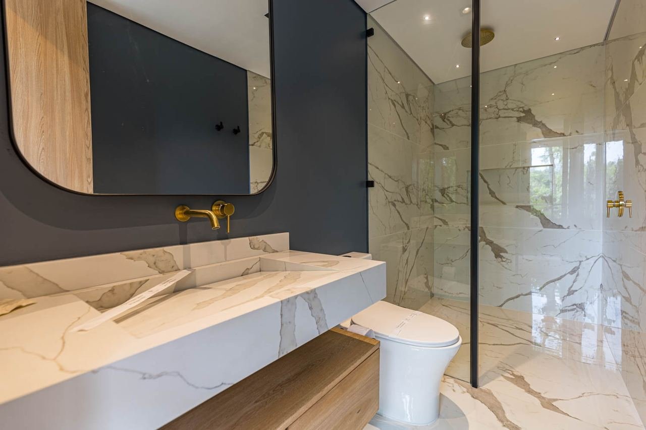Baño en mármol con lavamanos esculpido y grifería dorada