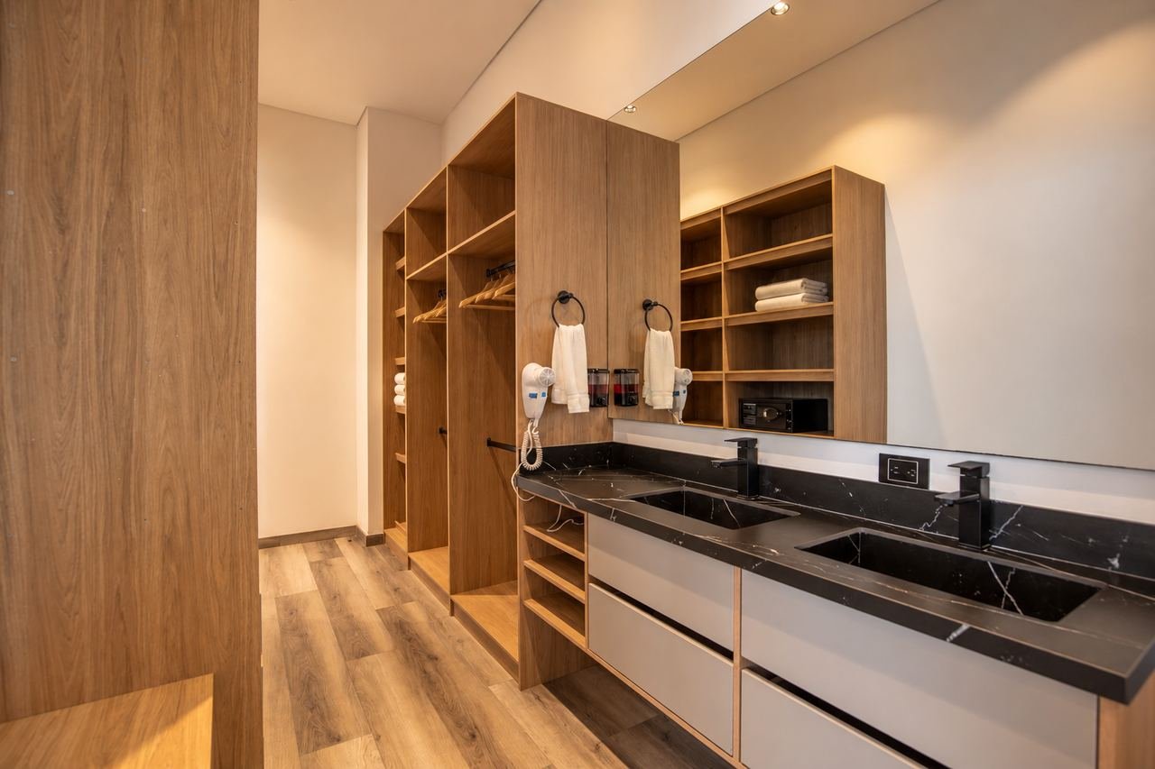 Mueble de lavamanos doble con mesón negro y carpintería en madera