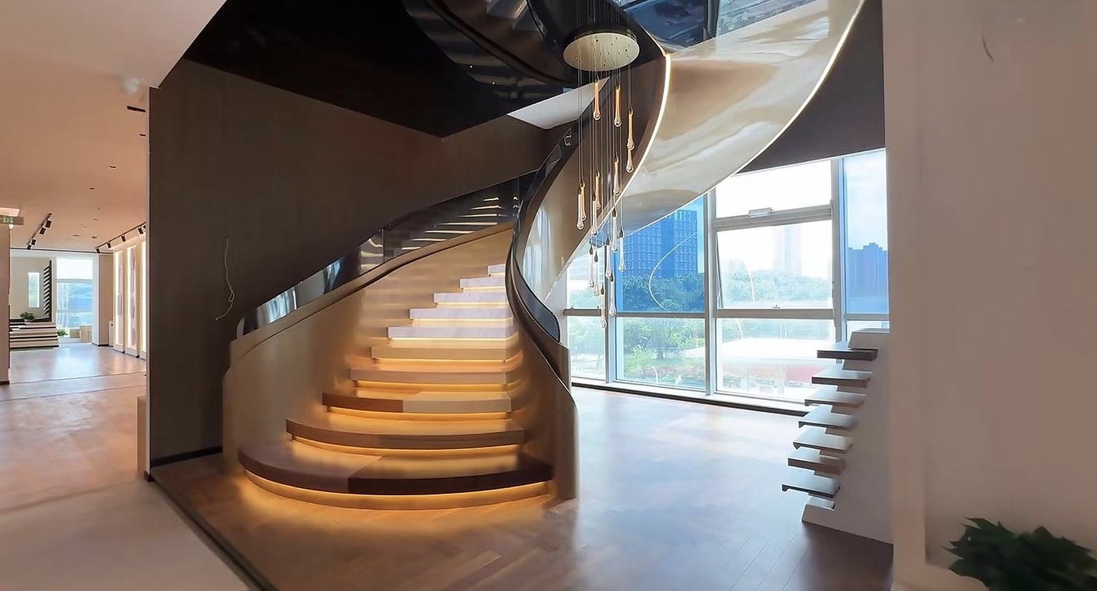 Escalera curva con huellas iluminadas y lámpara colgante