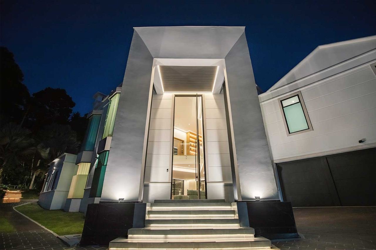 Acceso principal de la villa con escalera iluminada de noche