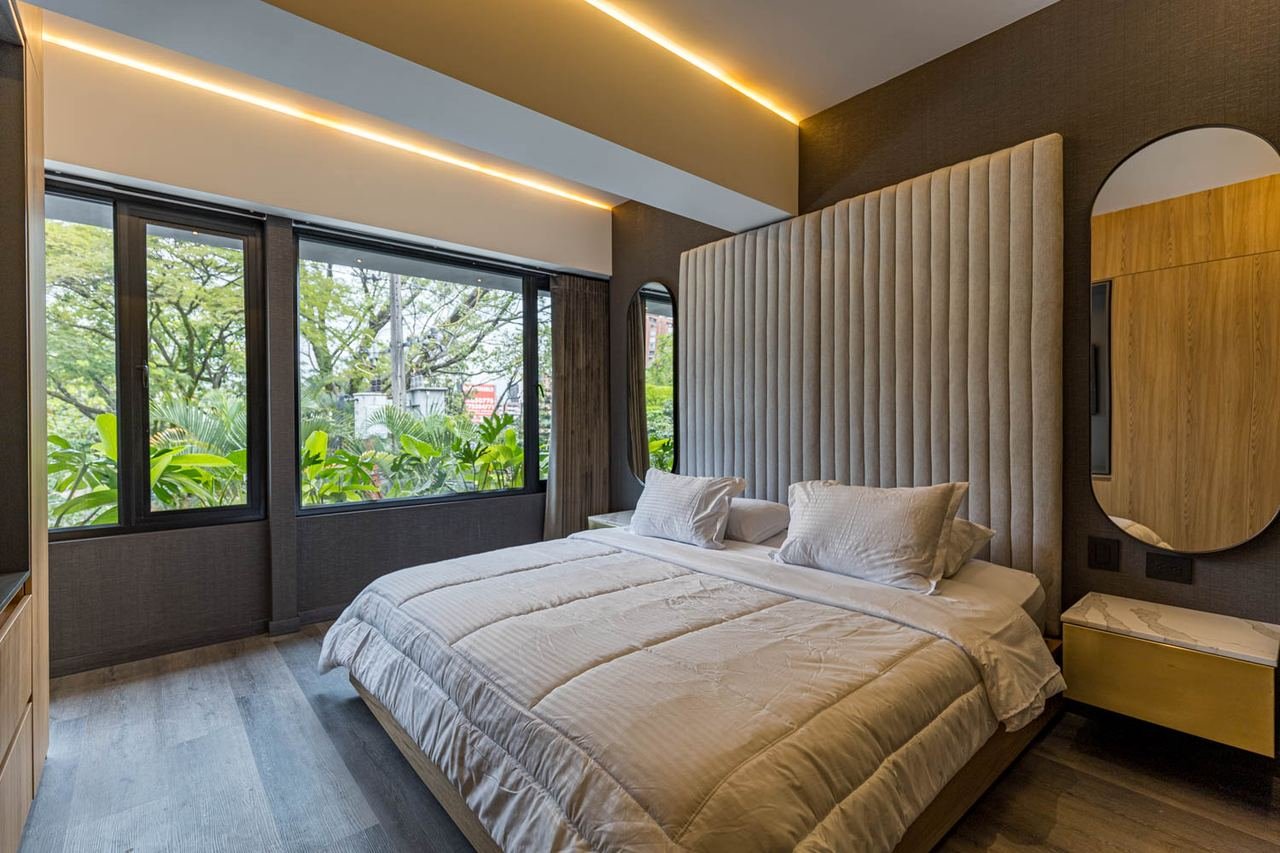 Habitación con cabecero tapizado de altura completa e iluminación indirecta