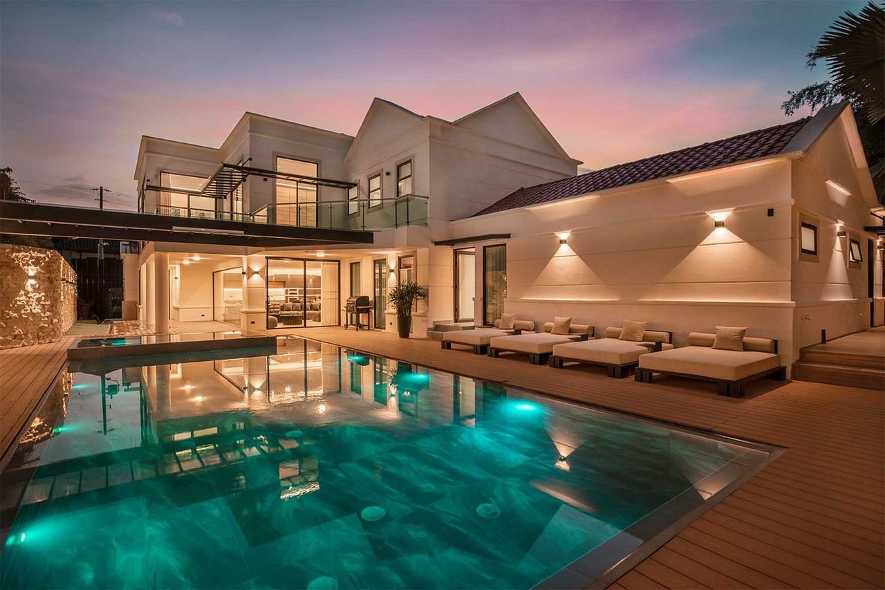 Villa at night with a lit pool in front of the façade