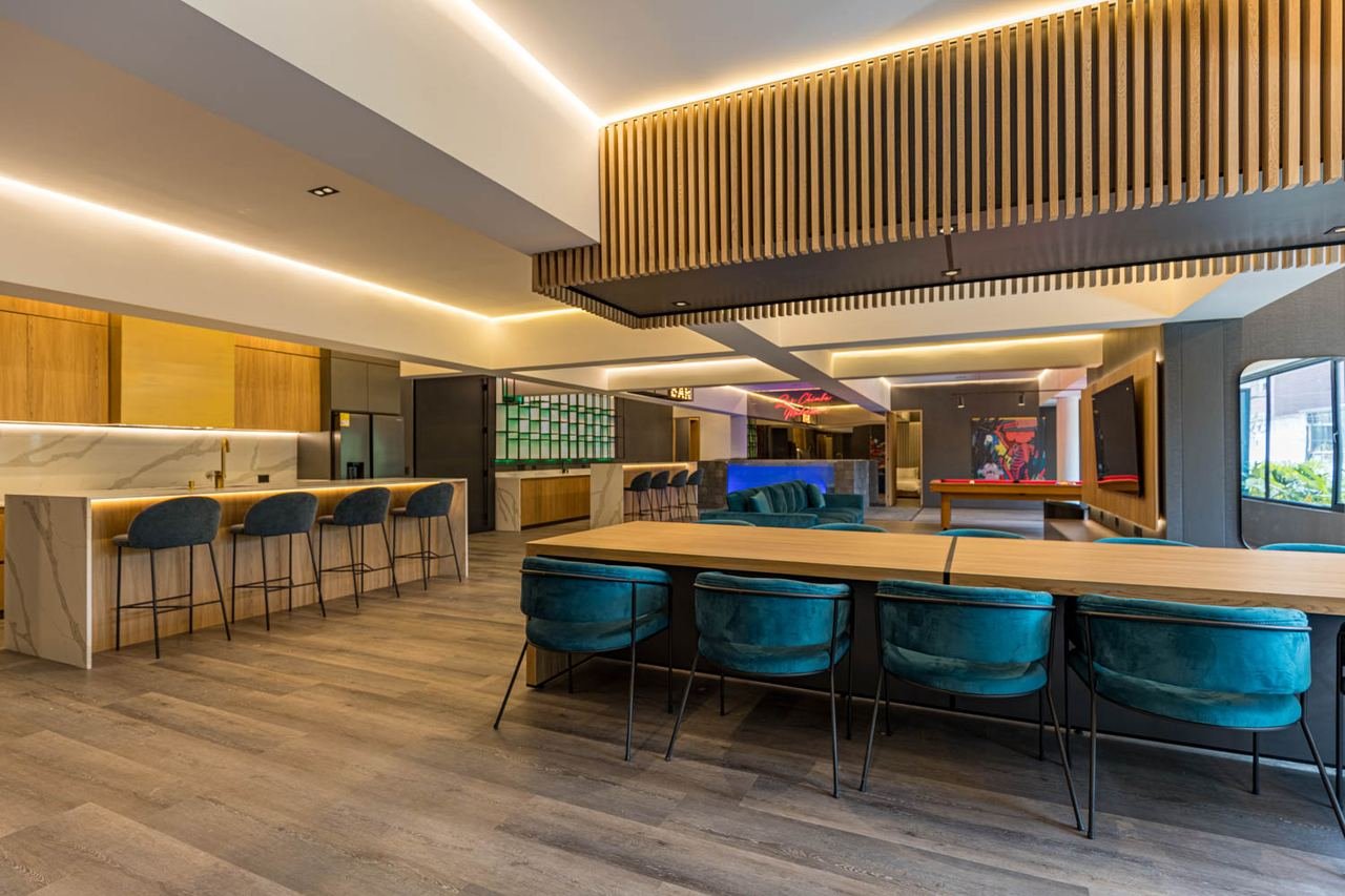 Zona social con barra, mesa larga en madera y cielo raso con listones